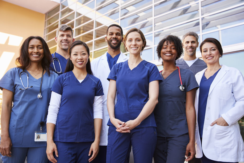 Smiling medical team standing together outside a hospital