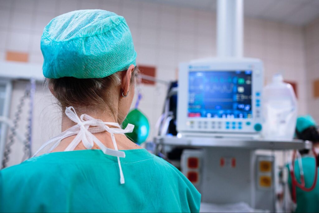 An anesthesiologist looks at a blurred monitor depicting her patient’s vitals.