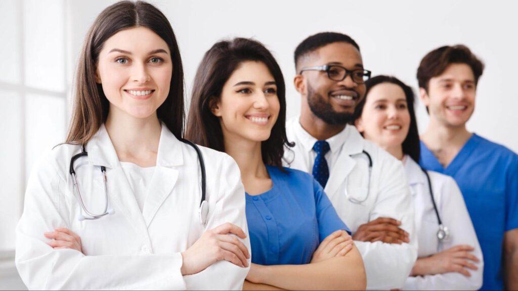 Five diverse healthcare professionals stand in a row.